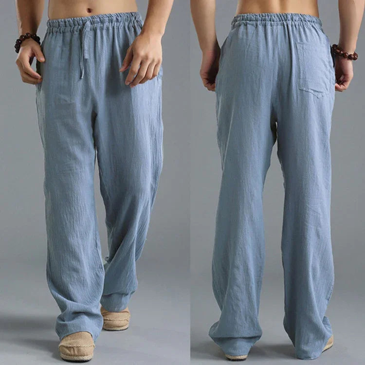Front and back views of men's light blue loose linen pants with elastic waistband and side pockets
