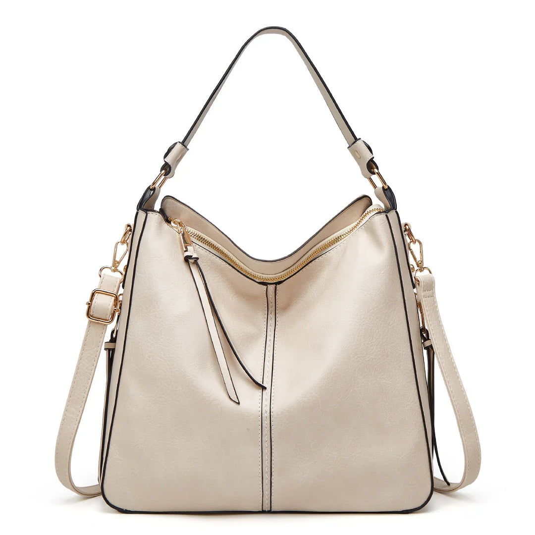 Cream leather shoulder bag with gold zipper, black trim, and adjustable strap