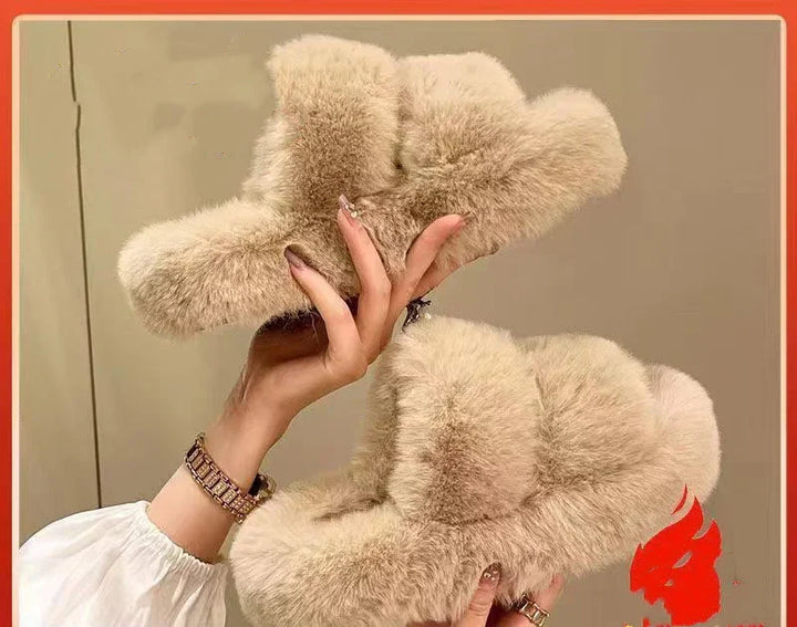 Hands holding a pair of beige fluffy indoor slippers with thick fur lining