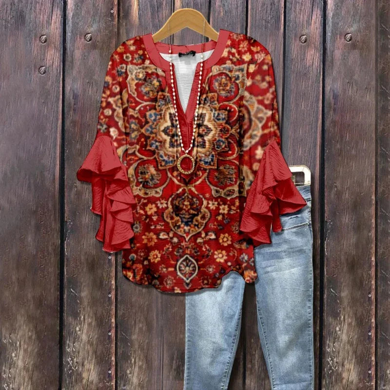 Red floral patterned blouse with ruffled sleeves and necklace paired with light blue jeans on wooden background