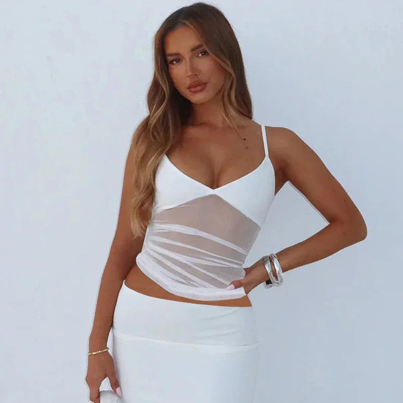 Woman modeling white mesh crop top and matching skirt with silver bracelets on plain white background