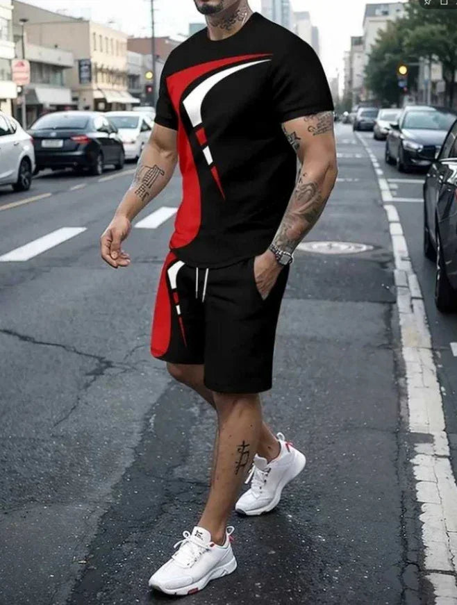 Man wearing black, red, and white graphic short-sleeve shirt and matching shorts with white sneakers on city street
