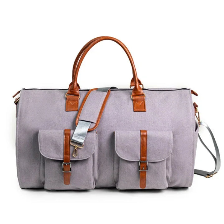 Gray canvas duffle bag with brown leather handles, dual front pockets, and gray shoulder strap