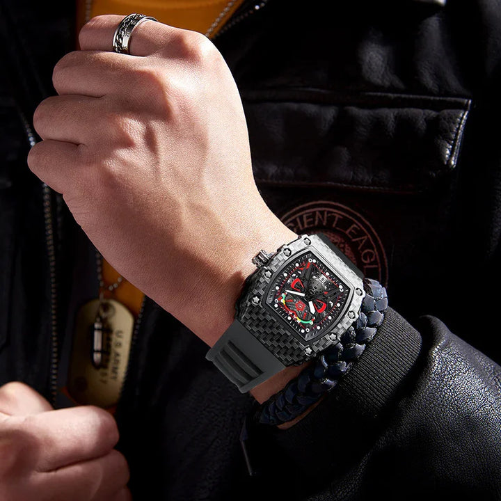 Man wearing a black carbon fiber luxury sports watch with red accents and a black braided leather bracelet