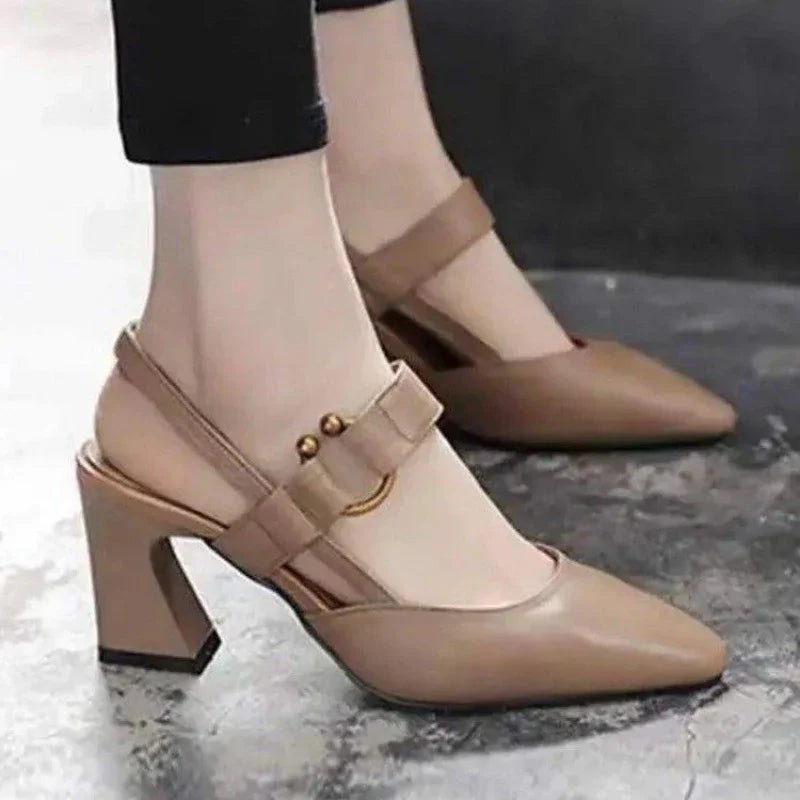 Woman wearing stylish beige pointed-toe block heel slingback shoes with decorative buckle strap