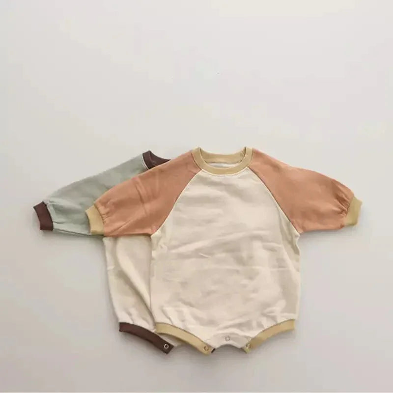Two baby rompers with short raglan sleeves, one beige with tan sleeves, the other cream with green sleeves