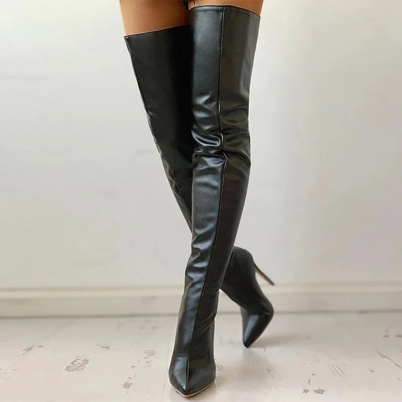 Woman wearing knee-high black leather stiletto boots standing on worn white floor