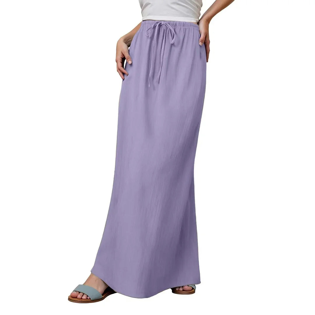 Woman wearing a long lavender drawstring skirt and blue slip-on sandals on white background