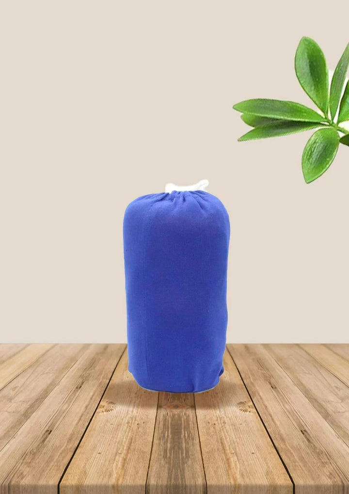 Blue stuffed pillow or cushion on wooden table with green plant leaves in background