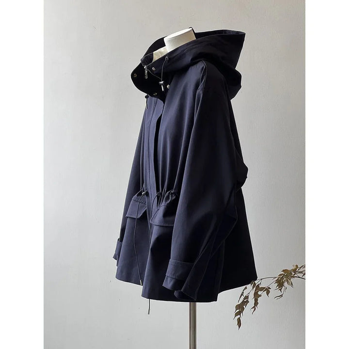 Navy blue hooded jacket with drawstrings and front pockets displayed on mannequin against plain wall