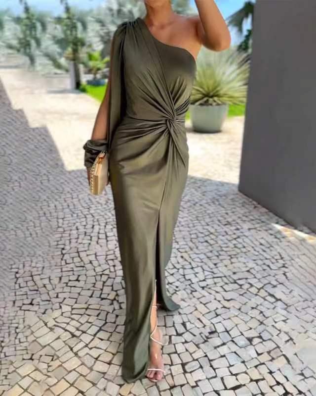 Woman in olive green one-shoulder ruched evening gown with side slit walking on cobblestone path