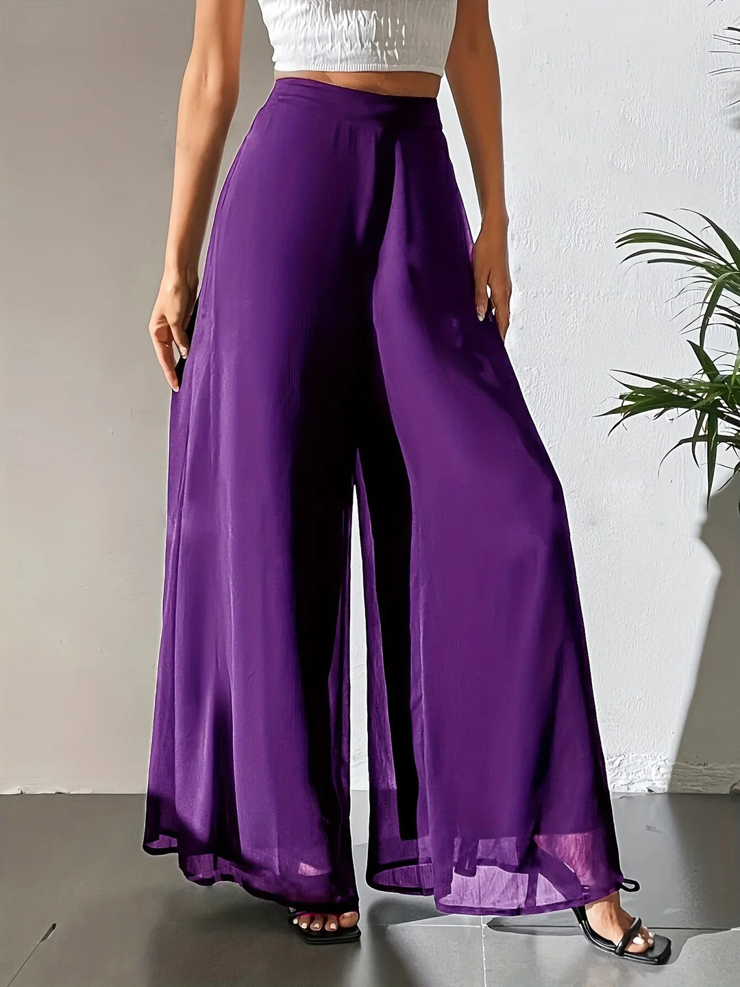 Woman wearing high-waisted purple wide-leg pants with a white crop top and black sandals