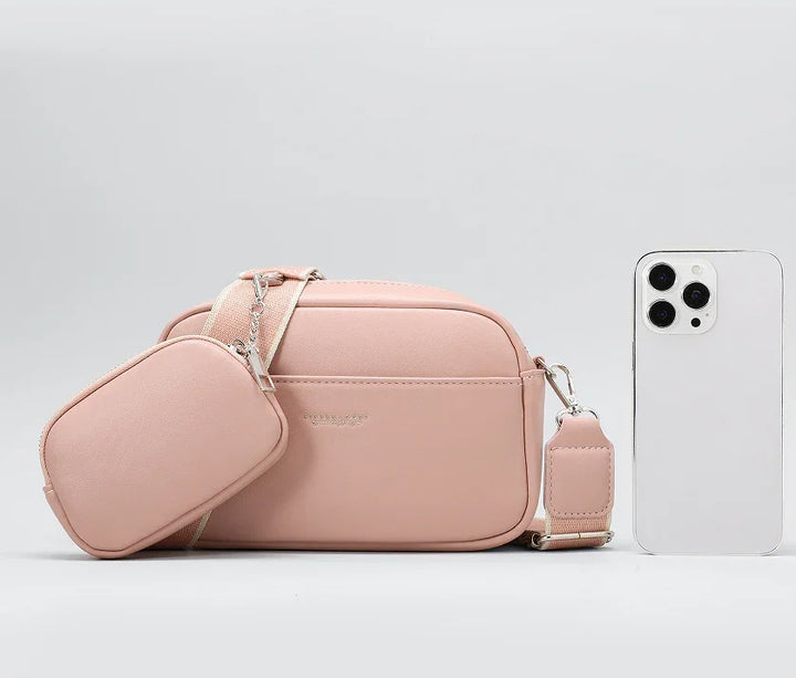 Blush pink crossbody bag with detachable pouch and adjustable strap next to white smartphone