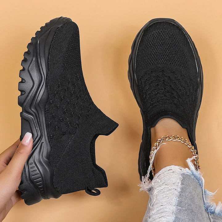 black knit slip-on sneakers with thick soles worn with distressed jeans and gold anklet
