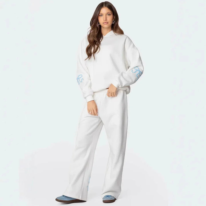 Woman wearing white casual hoodie and matching pants with blue sneakers on white background