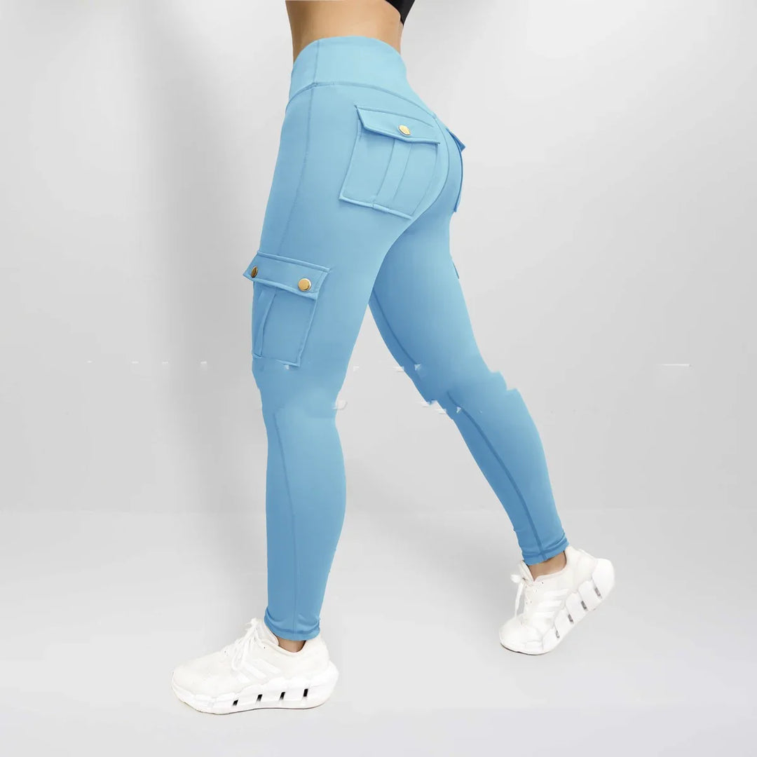 Woman wearing light blue cargo leggings with gold button pockets and white sneakers on gray background