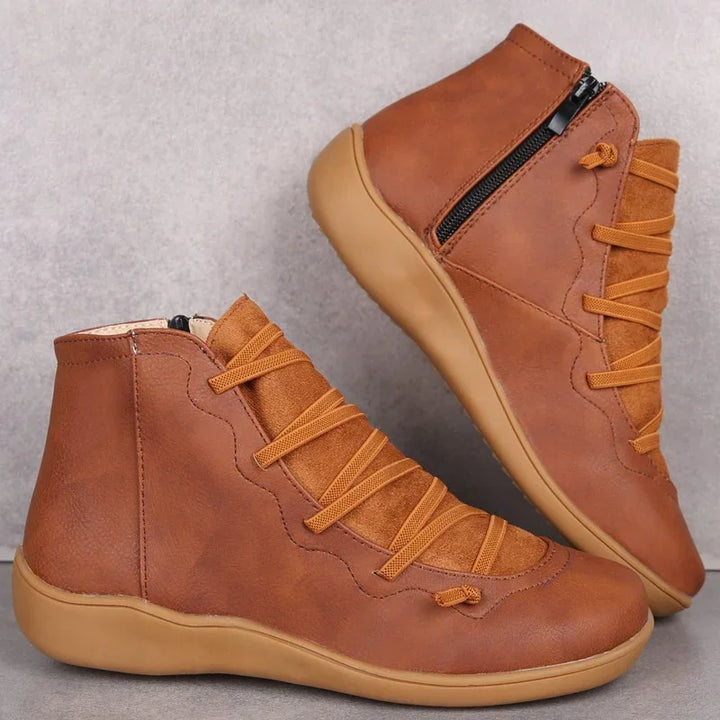 Brown leather ankle boots with side zipper, cushioned sole, and matching laces on gray background