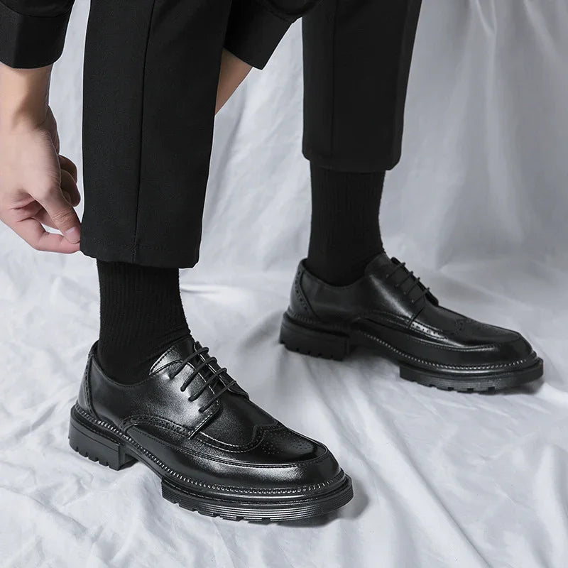 Close-up of black leather dress shoes worn with black socks and pants on a white fabric background