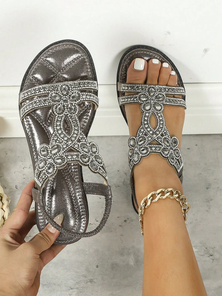 Women's metallic silver sandals with rhinestone flower embellishments and elastic ankle strap