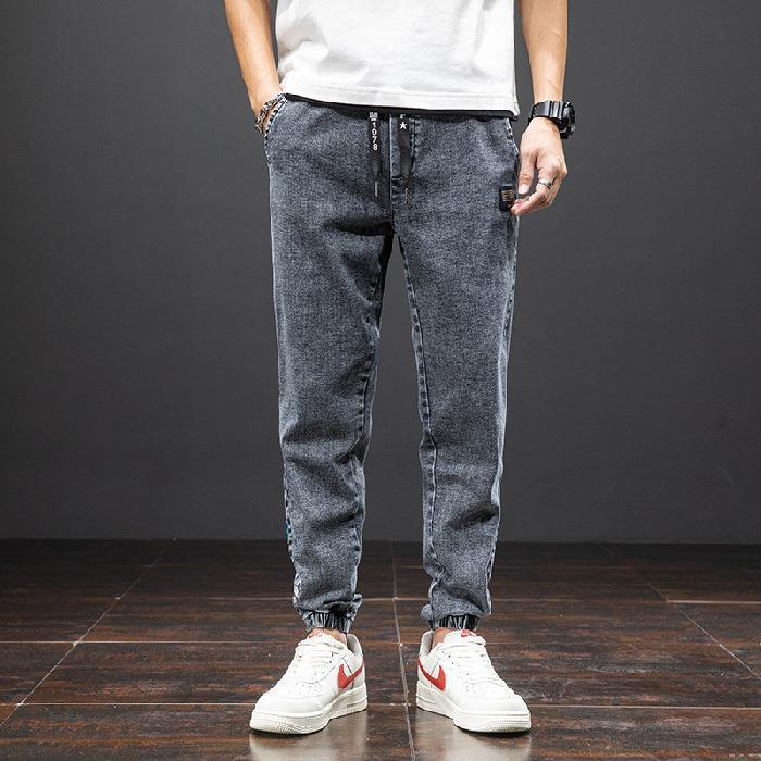 Man wearing grey casual jogger pants with elastic cuffs and white sneakers with red swoosh