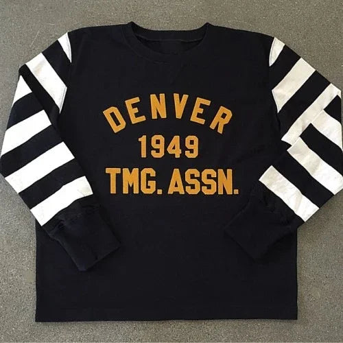 Black sweatshirt with white striped sleeves and yellow text reading Denver 1949 TMG. ASSN.